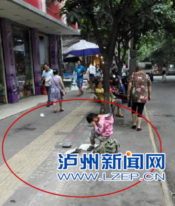 泸州一小女孩当街乞讨 其父在旁监督